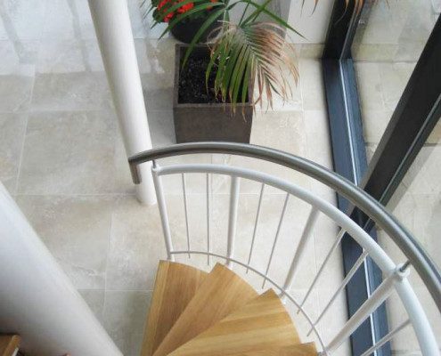 oak steps on a spiral stair with a tiled floor below