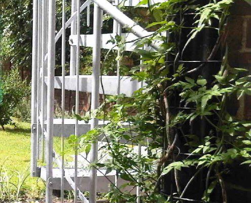external spiral staircase alongside some wall ivy