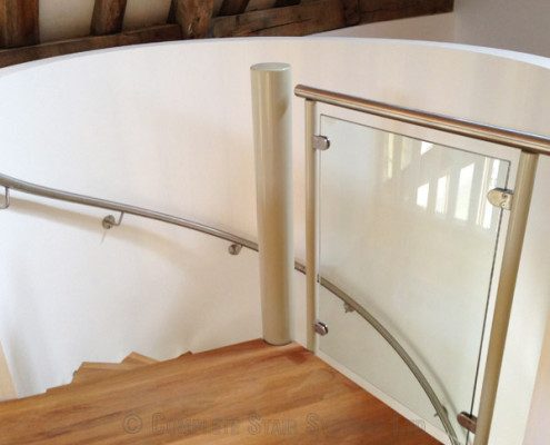 glass infill panel and white curved wall at the top of a stairwell
