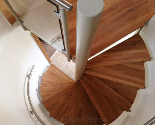 looking down an oak spiral stair with a stainless steel wall mounted handrail
