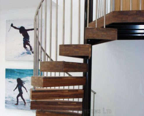 thick dark wood steps on a spiral stair with stainless spindles
