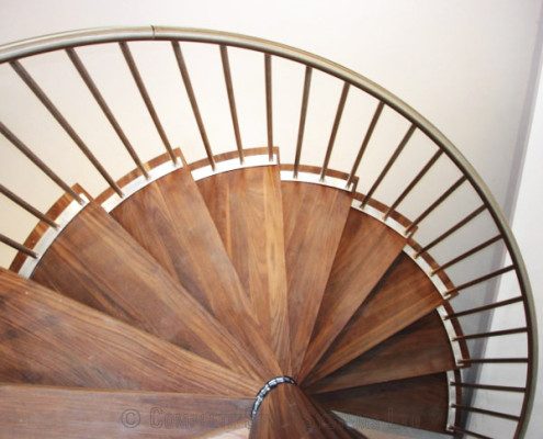 walnut steps on a spiral stair with a stainless handrail