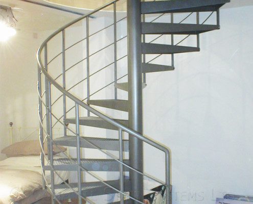 dark grey steel spiral staircase with white wall behind