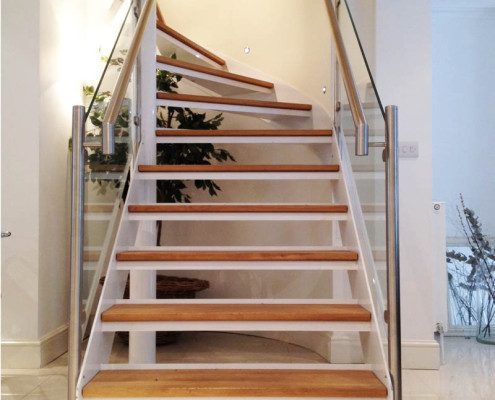 oak steps on an open riser staircase with glass panels