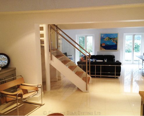 living area with black sofa behind a white steel spiral staircase