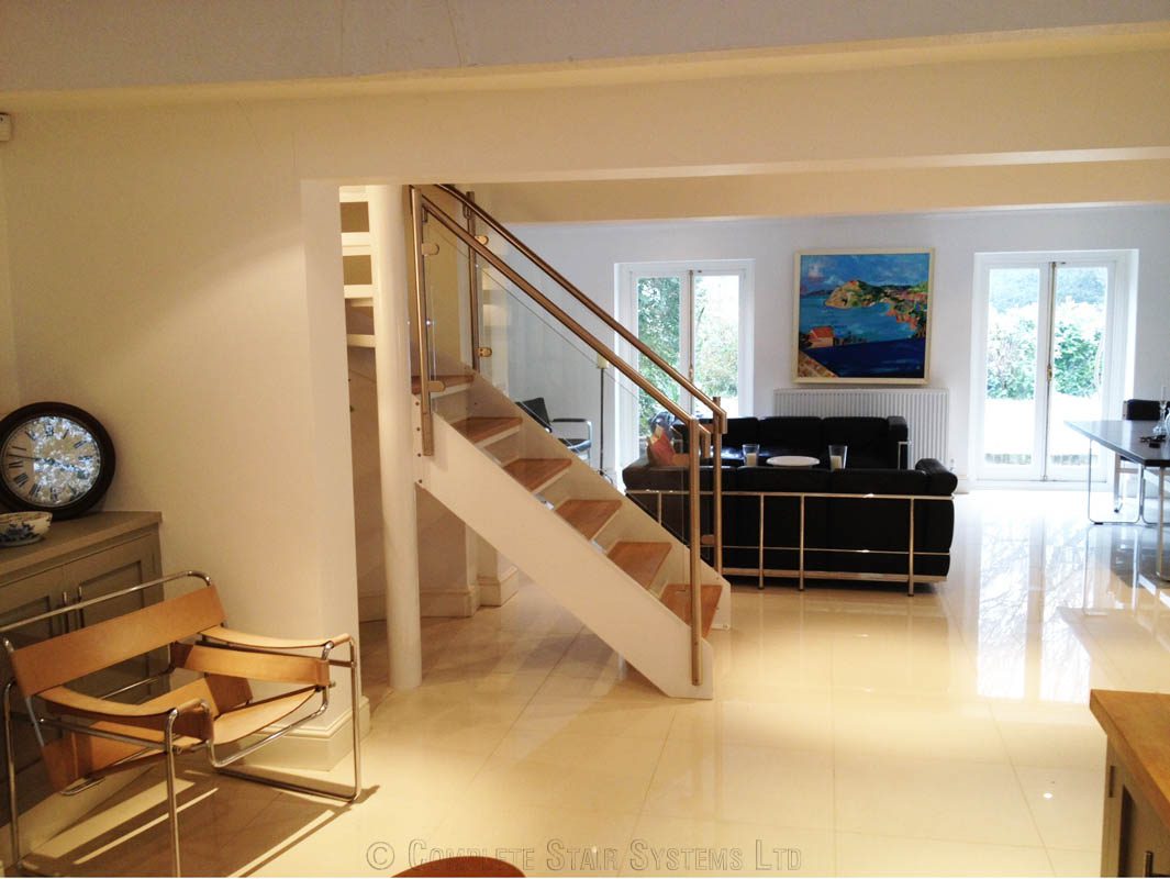 living area with black sofa behind a white steel spiral staircase