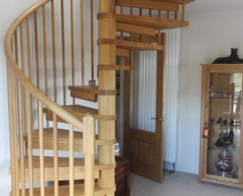 oak spiral stair leading up in a carpeted living room