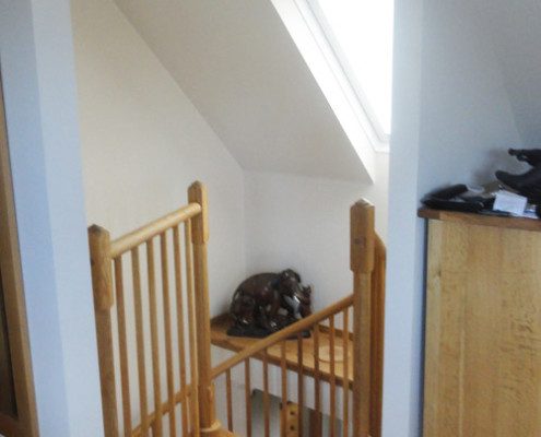 oak platform at the top of spiral staircase with a roof window