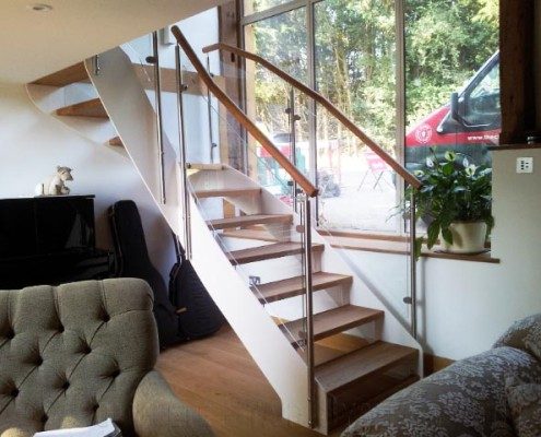 white steel stair with open risers and glass panels with sofas around