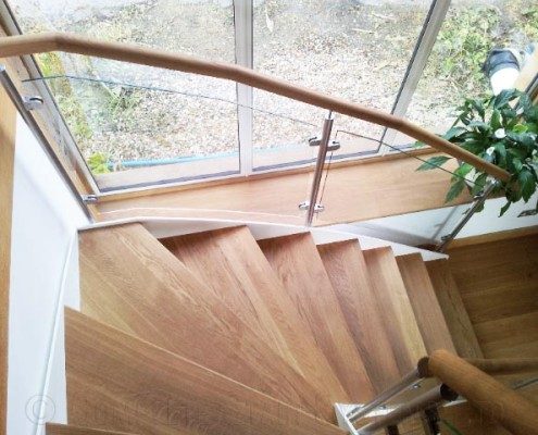 oak steps and glass panels on a stair in front of a window