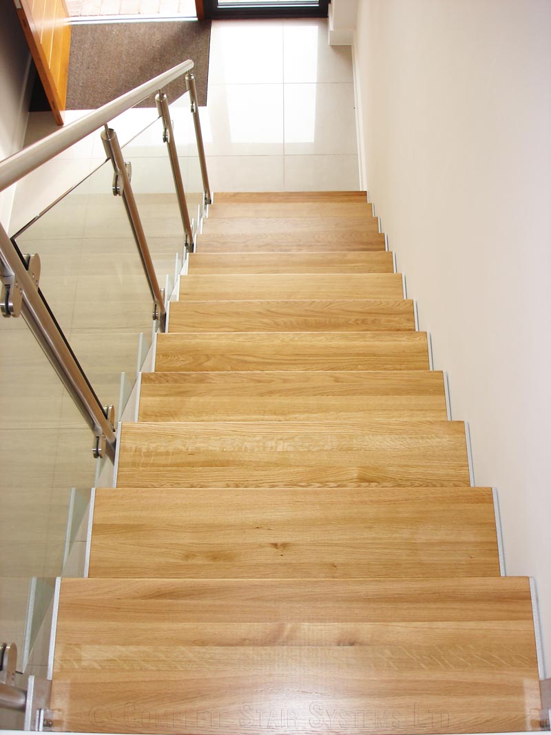 Bespoke Staircase Poole - Model 500 oak steps on a staircase with glass panels to side and hallway below