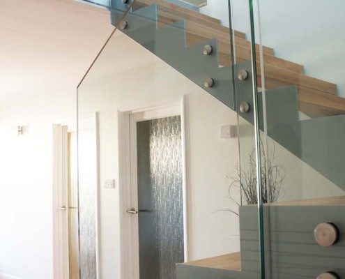 grey steel stringers with glass panels on a staircase