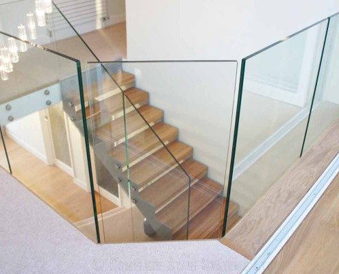 glass panels around an opening featuring a oak and steel staircase