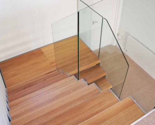 oak steps on a half turn staircase with glass staircase