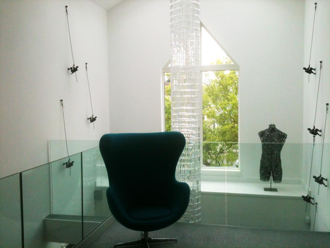 void above a hallway with circular suspended light and frameless glass balustrade