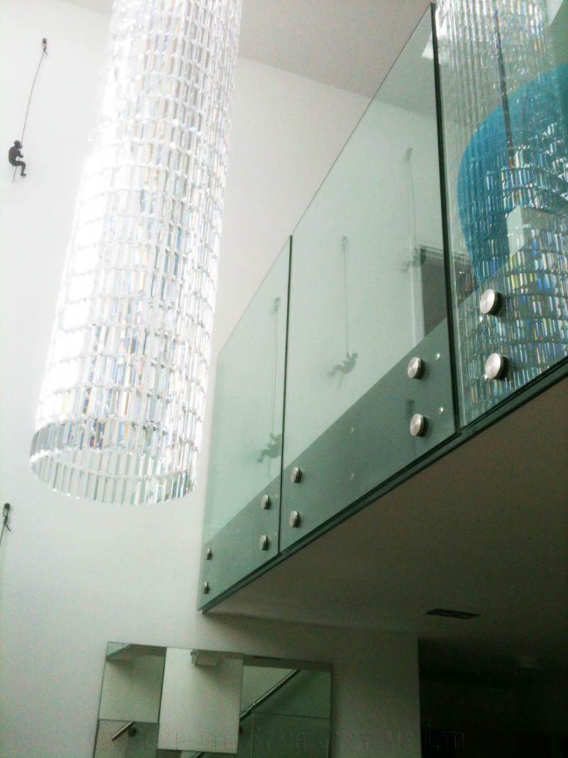 light cylinder hanging from ceiling with frameless glass balustrade