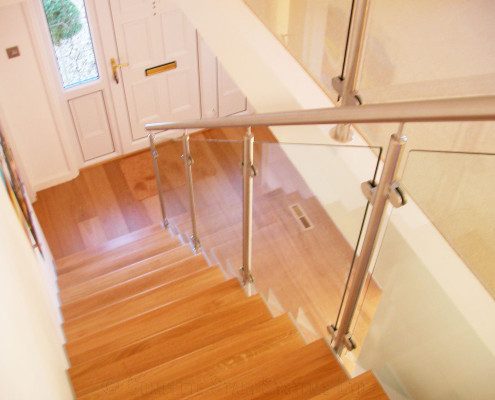 looking down a stairwell to a white front door with timber floor