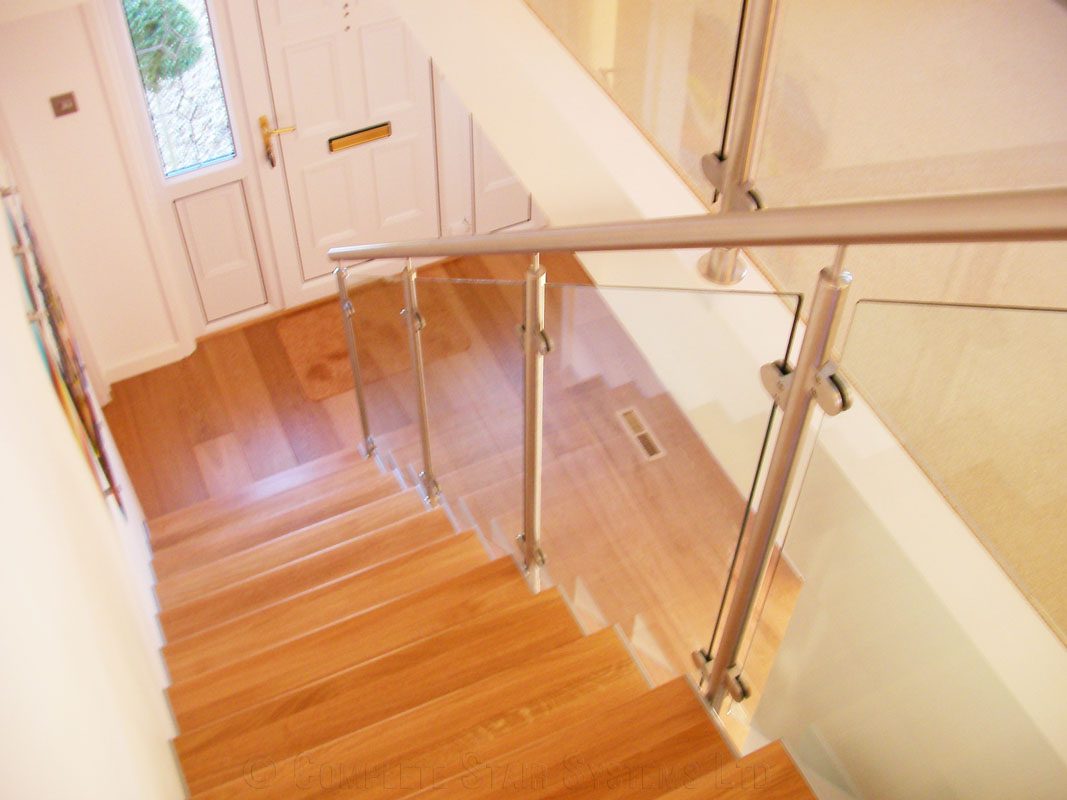 looking down a stairwell to a white front door with timber floor