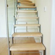 open riser staircase with light wood steps and stainless riser bars