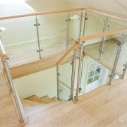 glass balustrade around stairwell with light wood floor upstairs