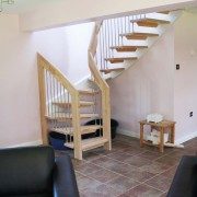 open plan living area with black seats and half turn staircase with open risers