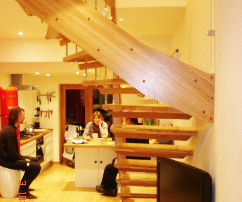 glass panel on open staircase with 2 people in kitchen behind