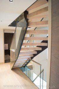 back view of thick wooden steps on a black steel and glass stair in a home