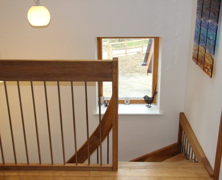 stairwell with oak floor and oak and stainless landing balustrade