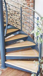 oak steps on a steel spiral staircase with a stone wall behind