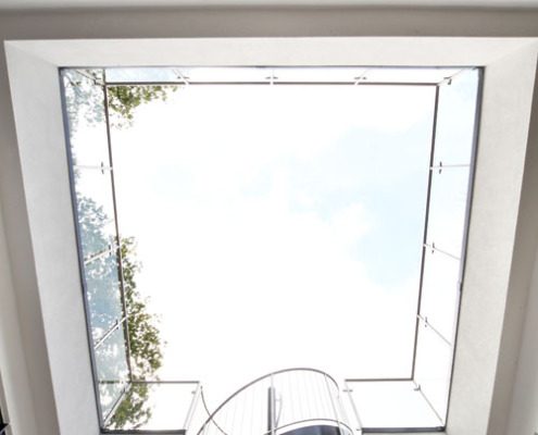 looking up at the glass balustrade around a court year with black spiral staircase and glass treads