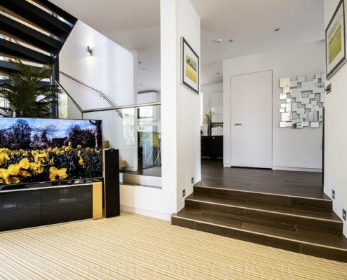 carpeted lounge area with a large television and spiral staircase leading up