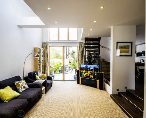 lounge with black sofa with tv and spiral stair at the back