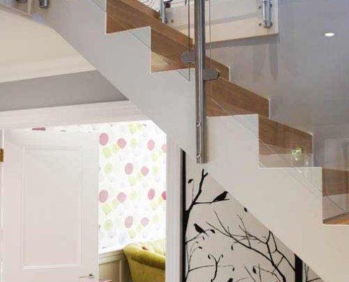 hallway with white stair staircase with glass panels Infront of wallpapered wall