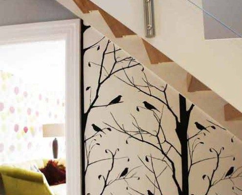 black tree designed wallpaper behind white steel staircase with glass panels