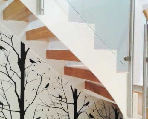 white steel stringer on staircase with tree designed wallpaper to rear