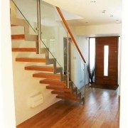 glass panels down the side of a steel and wood staircase in a hallway