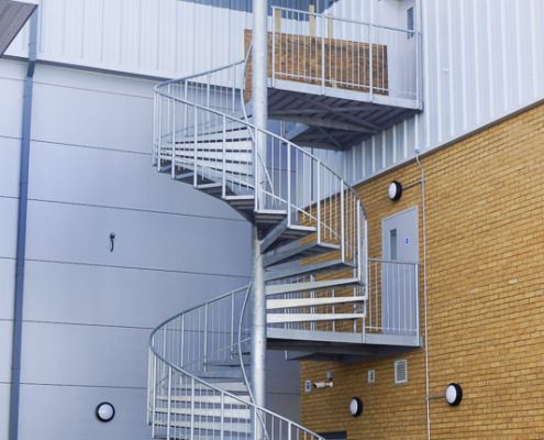 back of commercial building with double flight spiral stair with canopy above