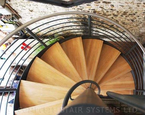 oak tread spiral staircase with stone wall behind