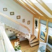 timber frames living room with quarter turn staircase running up against a white wall with landing balustrade