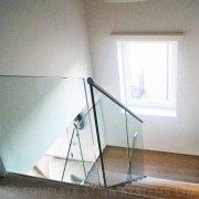 looking down a half turn staircase with timber steps and glass balustrade