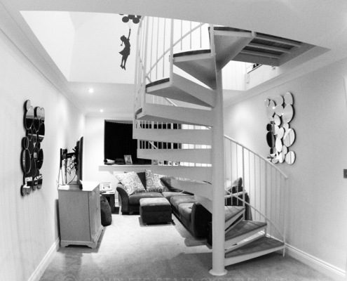 black and white shot of a white spiral stair and living room beyond
