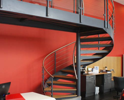 double height red spiral stair with grey spiral stair with glass panels on balcony
