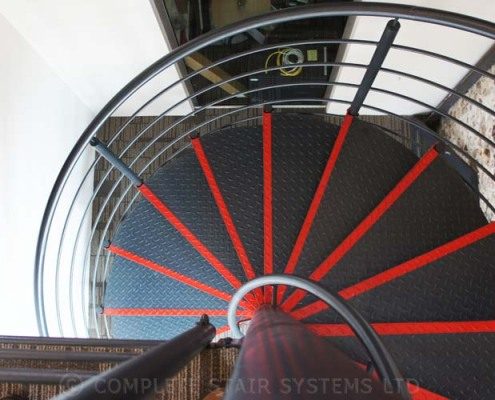 looking down on a steel stair painted black with red strips to front of steps