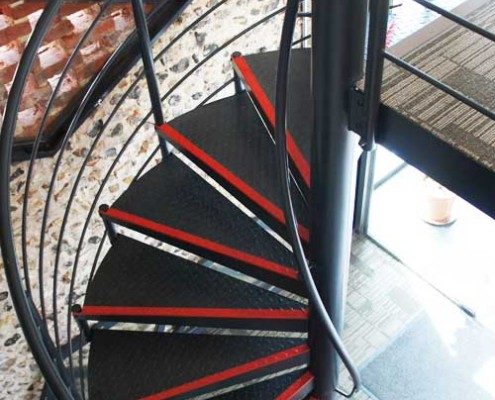black spiral staircase with traditional stone wall behind