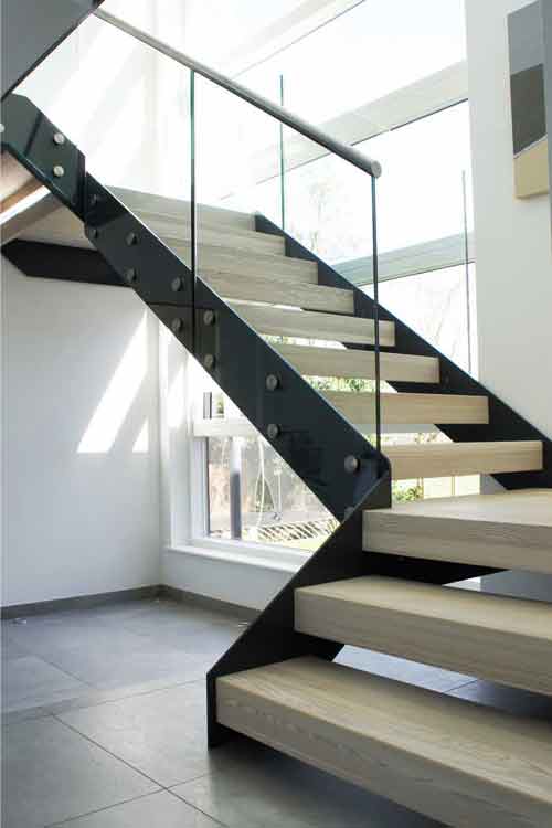 black steel staircase in front of a window with glass panels and timber treads
