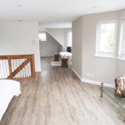 upstairs bedroom with timber floor and landing balustrade above stairwell with stainless spindles