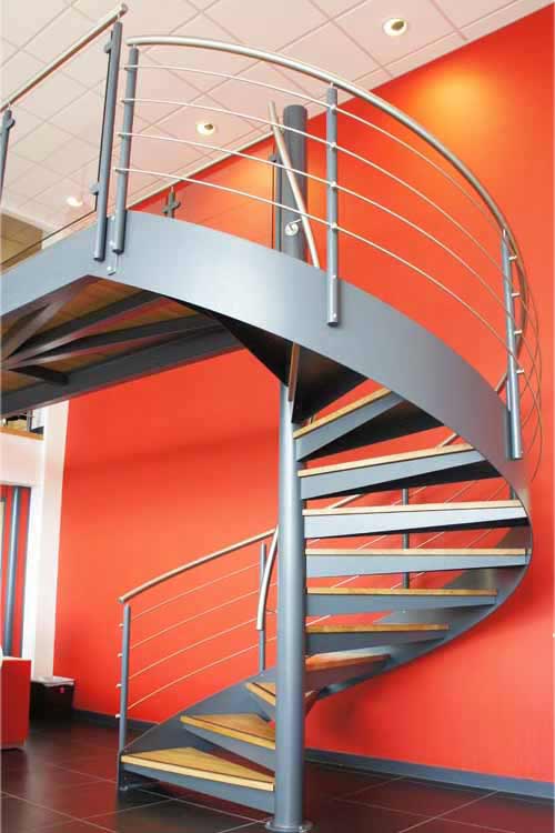 large red wall behind a dark grey spiral staircase with stainless steel handrail
