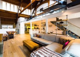 mezzanine above a large living space with grey sofa and dining table
