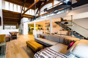 mezzanine above a large living space with grey sofa and dining table