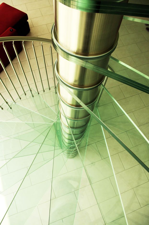 close up on glass step spiral staircase and stainless steel spindles